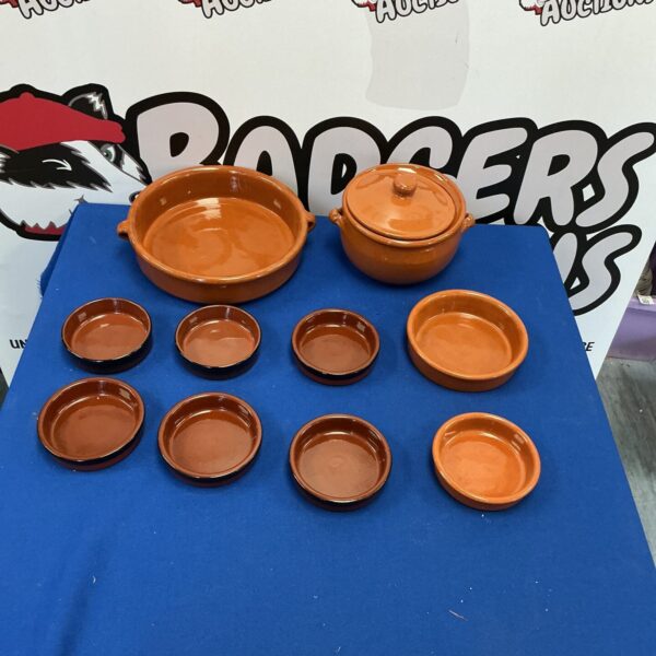 Six vintage earthenware kitchen pots on a blue surface.