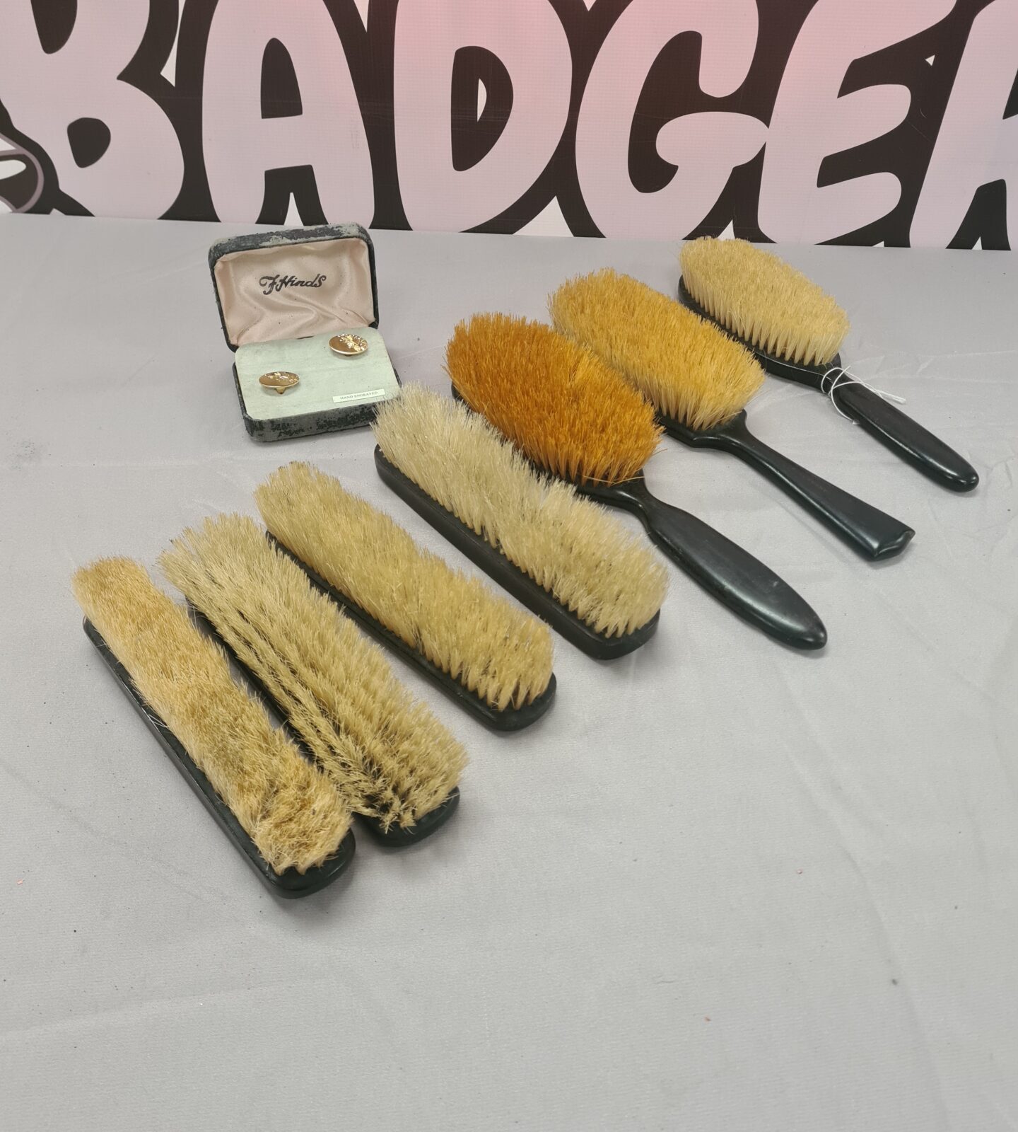 Vintage ebony brush set with cufflinks on a patterned background.