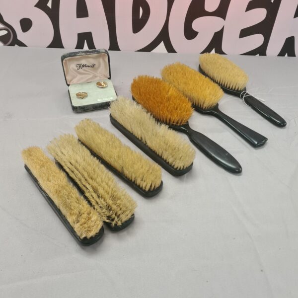 Vintage ebony brush set with cufflinks on a patterned background.