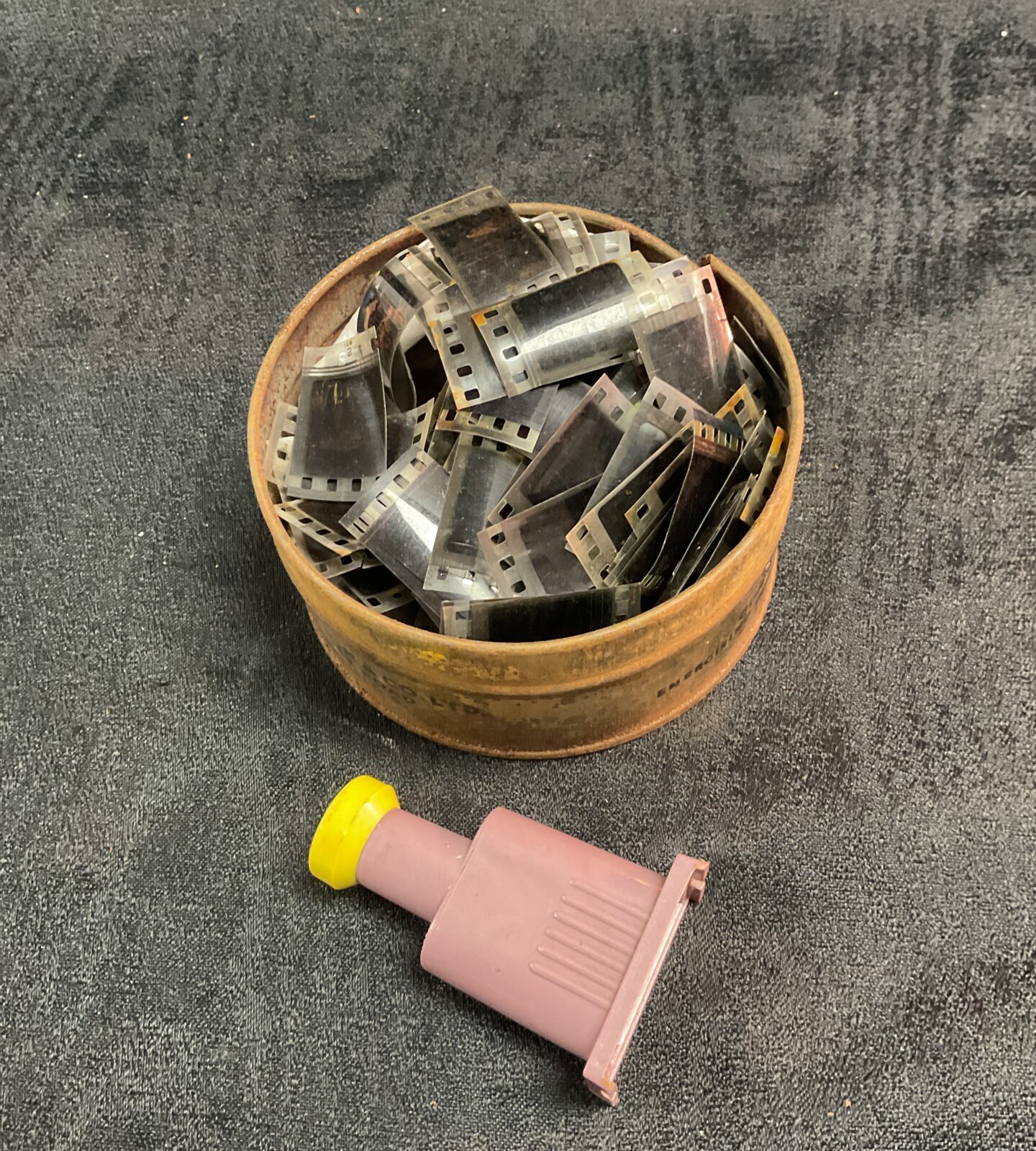 Vintage tin filled with 8mm film reels and a film viewer.