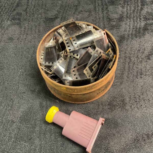 Vintage tin filled with 8mm film reels and a film viewer.