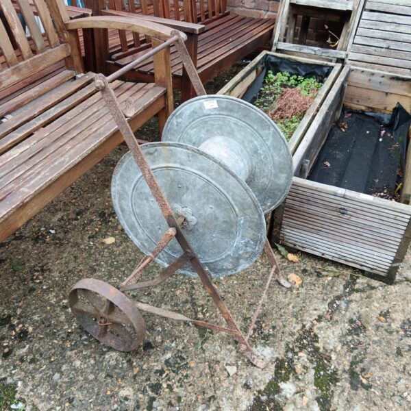 Vintage galvanised hose reel for garden hose storage.
