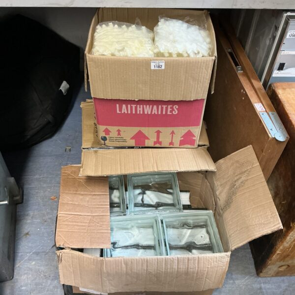 Two boxes of vintage glass bricks with spacers for building projects.