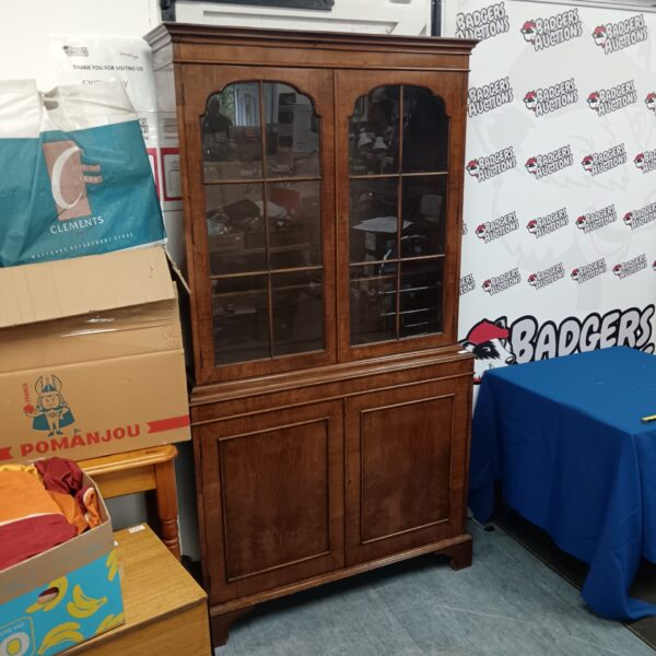 Vintage glass front bookcase with detailed wood finish.