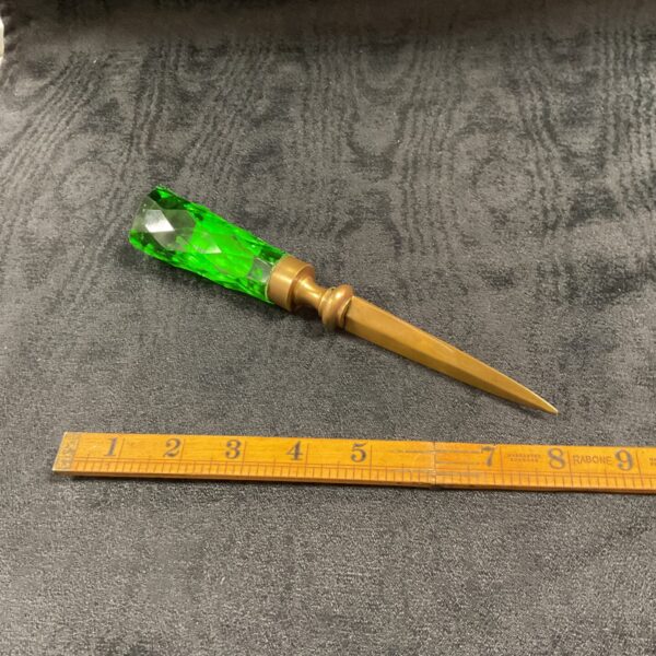 Vintage green glass and brass letter opener on a white surface.