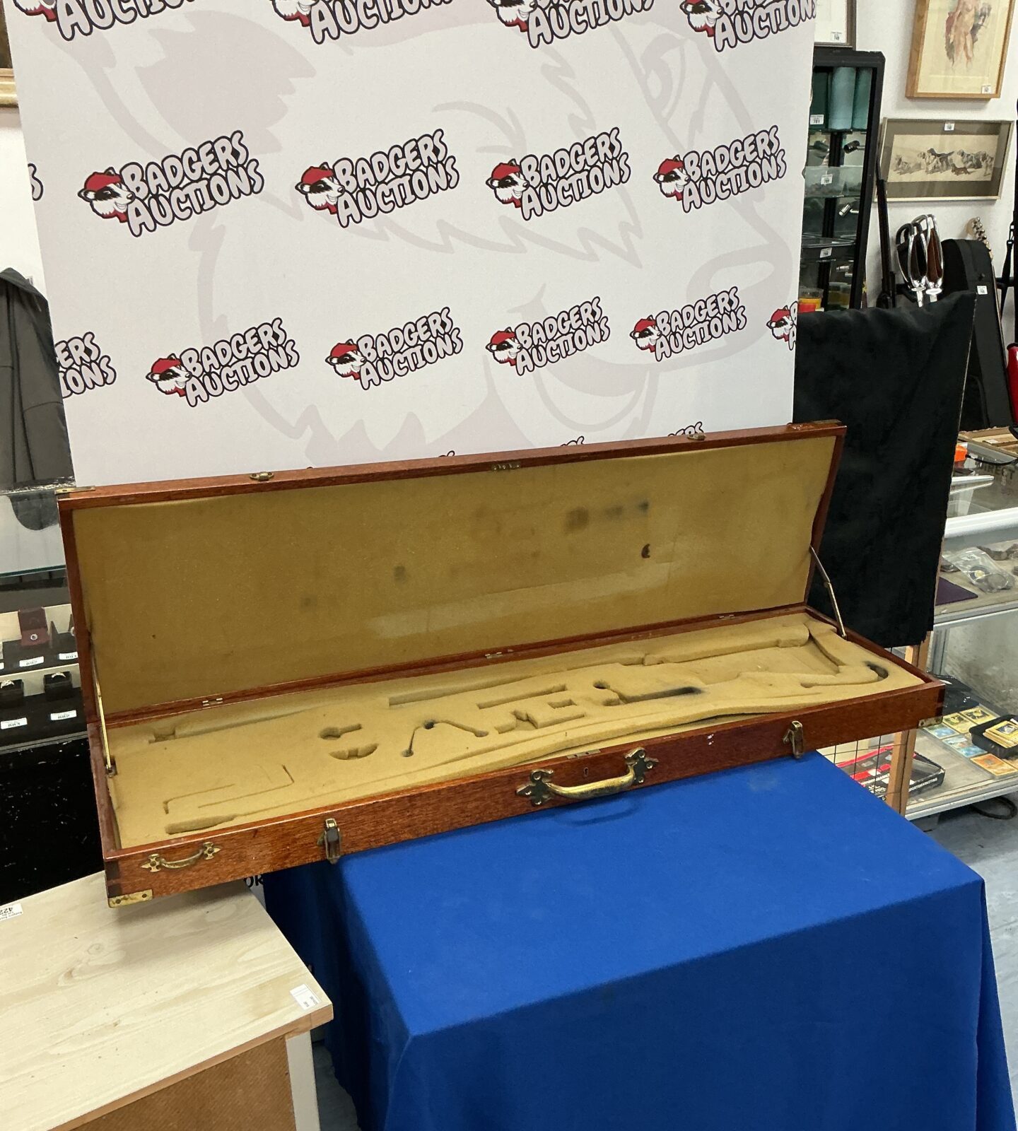 Side view of a vintage wooden gun case with a blue cloth covering.