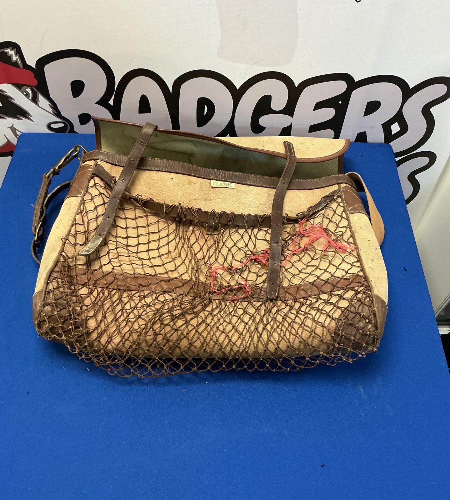 Vintage hunting game bag with woven mesh and leather strap.