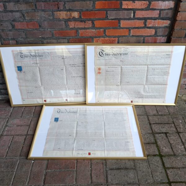 Three vintage indentures in gilt frames with wax seals.