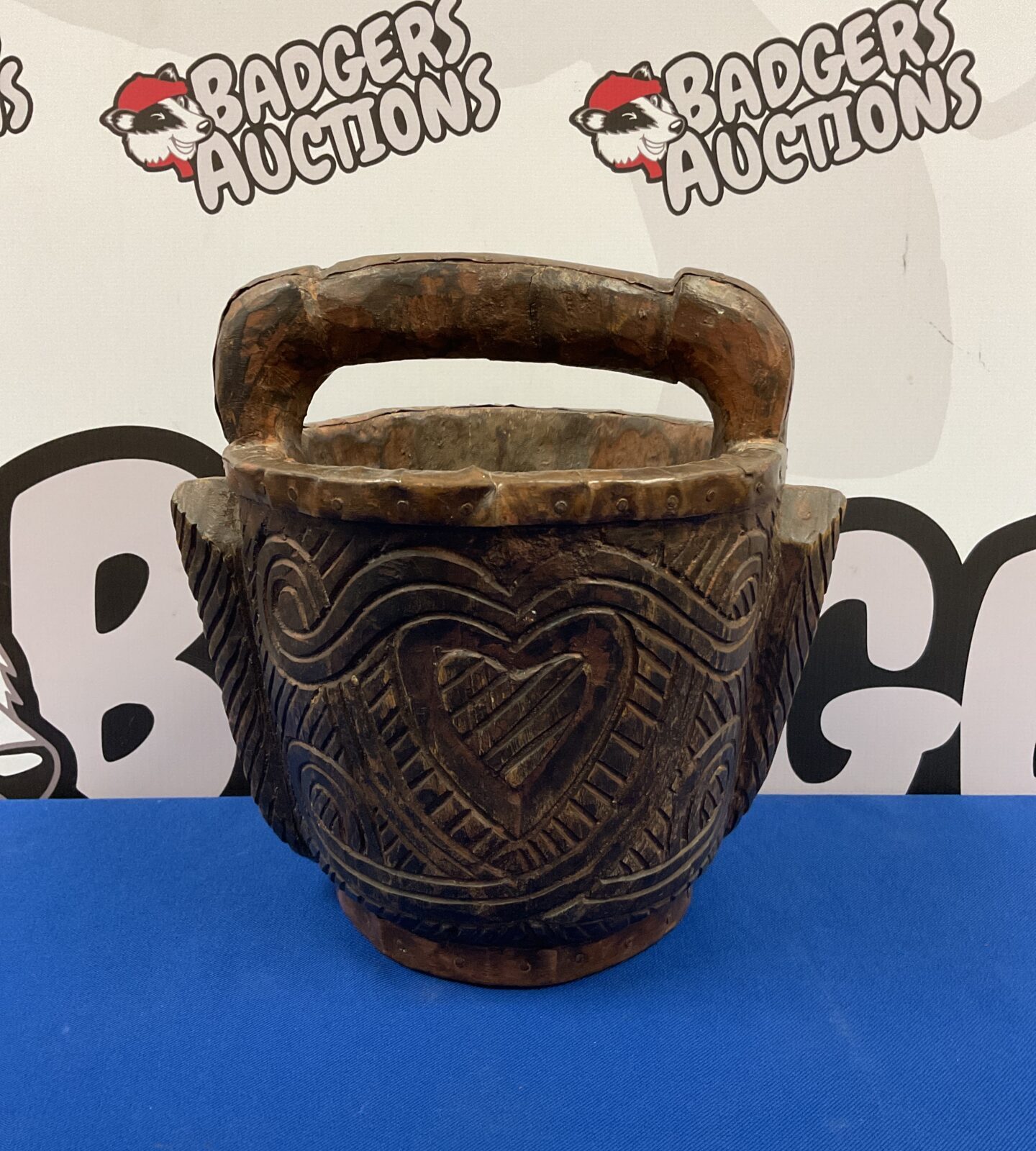 Intricate carvings on a vintage Indian wooden bucket with copper rim.