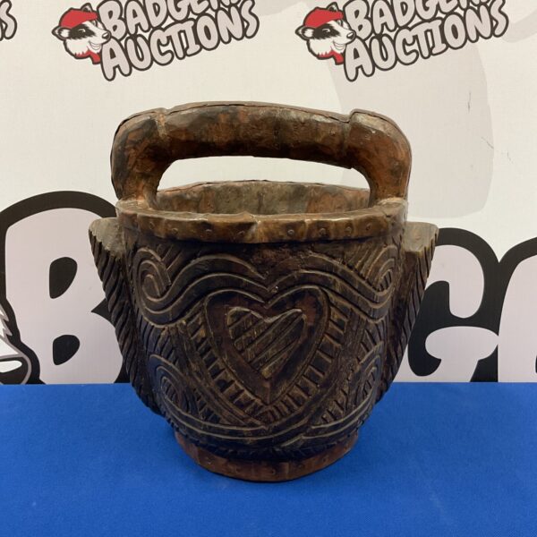 Intricate carvings on a vintage Indian wooden bucket with copper rim.