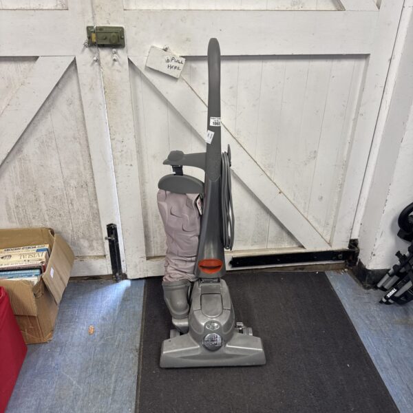 Front view of a vintage Kirby vacuum cleaner with attachments.