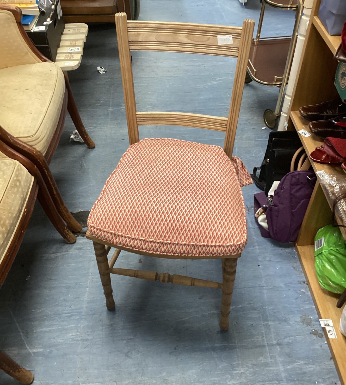 Vintage ladder back chair with patterned seat and spindle legs.