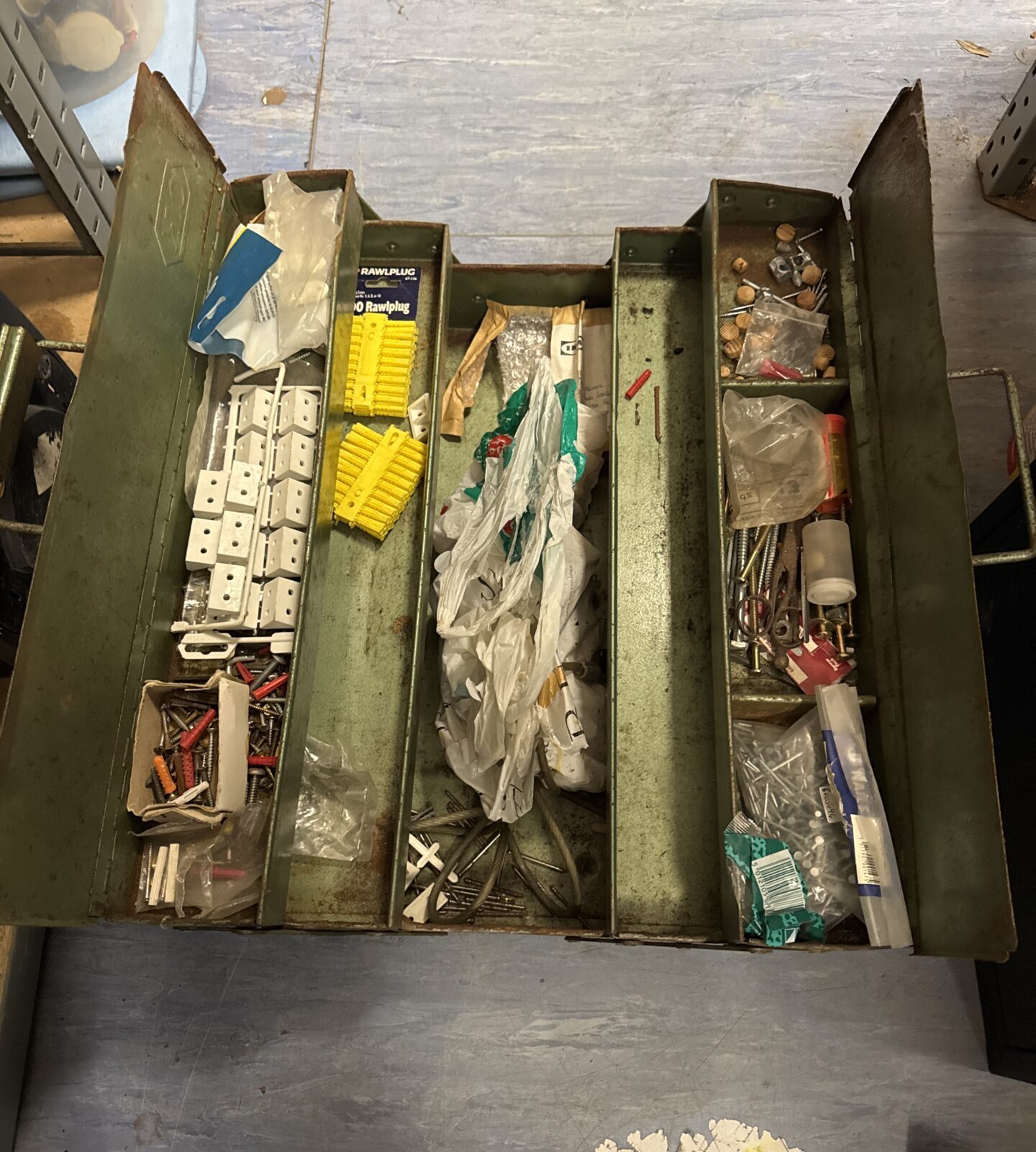 Vintage metal cantilever toolbox filled with various tools and parts.