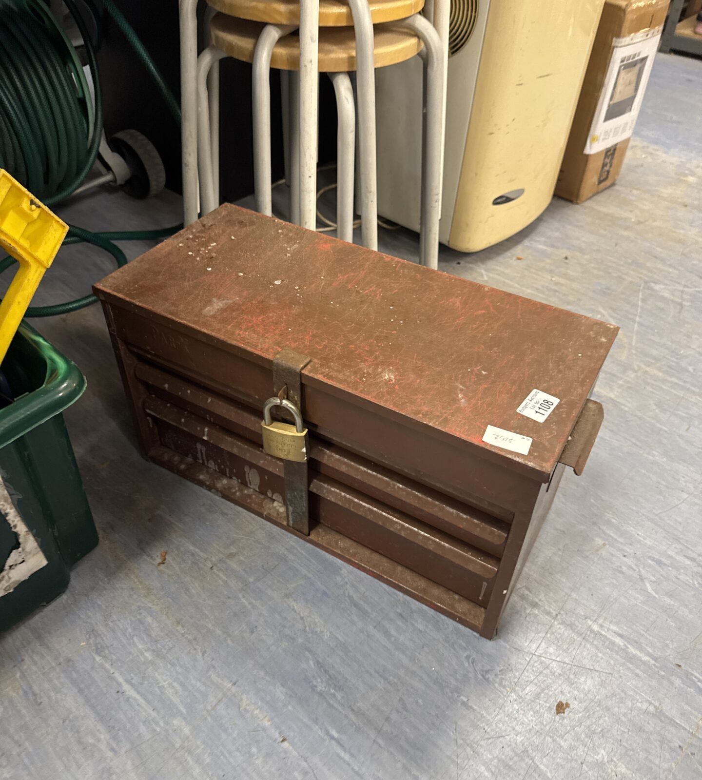 Locked vintage metal toolbox with padlock, antique tool storage.