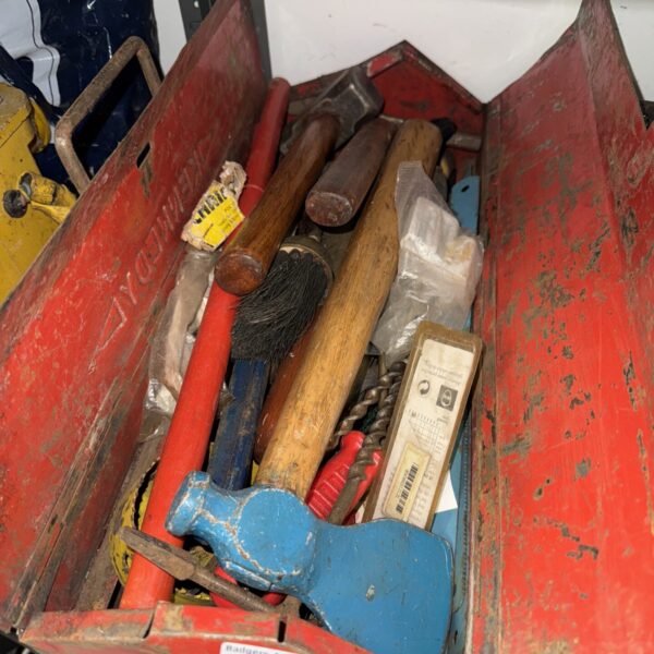 Vintage metal toolbox filled with antique hand tools for workshop storage.