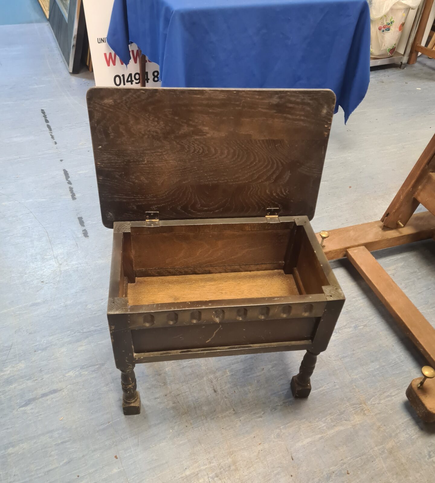 Side view of a vintage oak sewing table with turned legs.