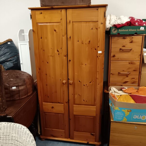 Vintage pine cupboard with two doors and shelving for storage.