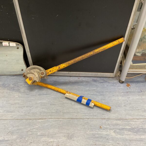 Vintage yellow pipe bender for metalworking and plumbing projects.