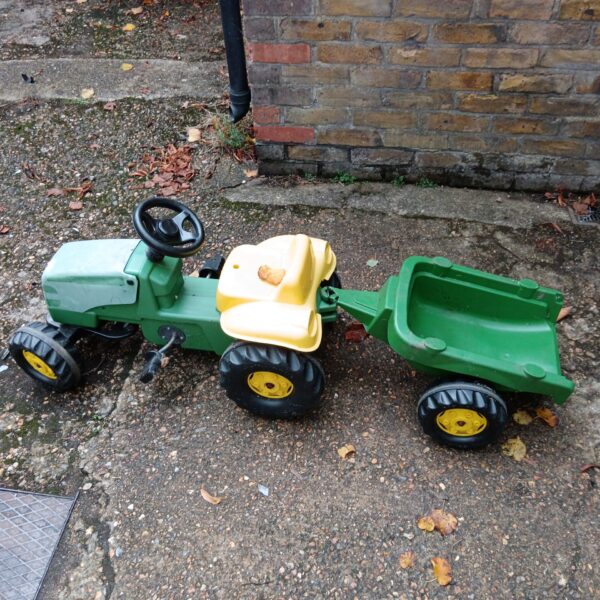 Bright green vintage ride on tractor with yellow trailer.
