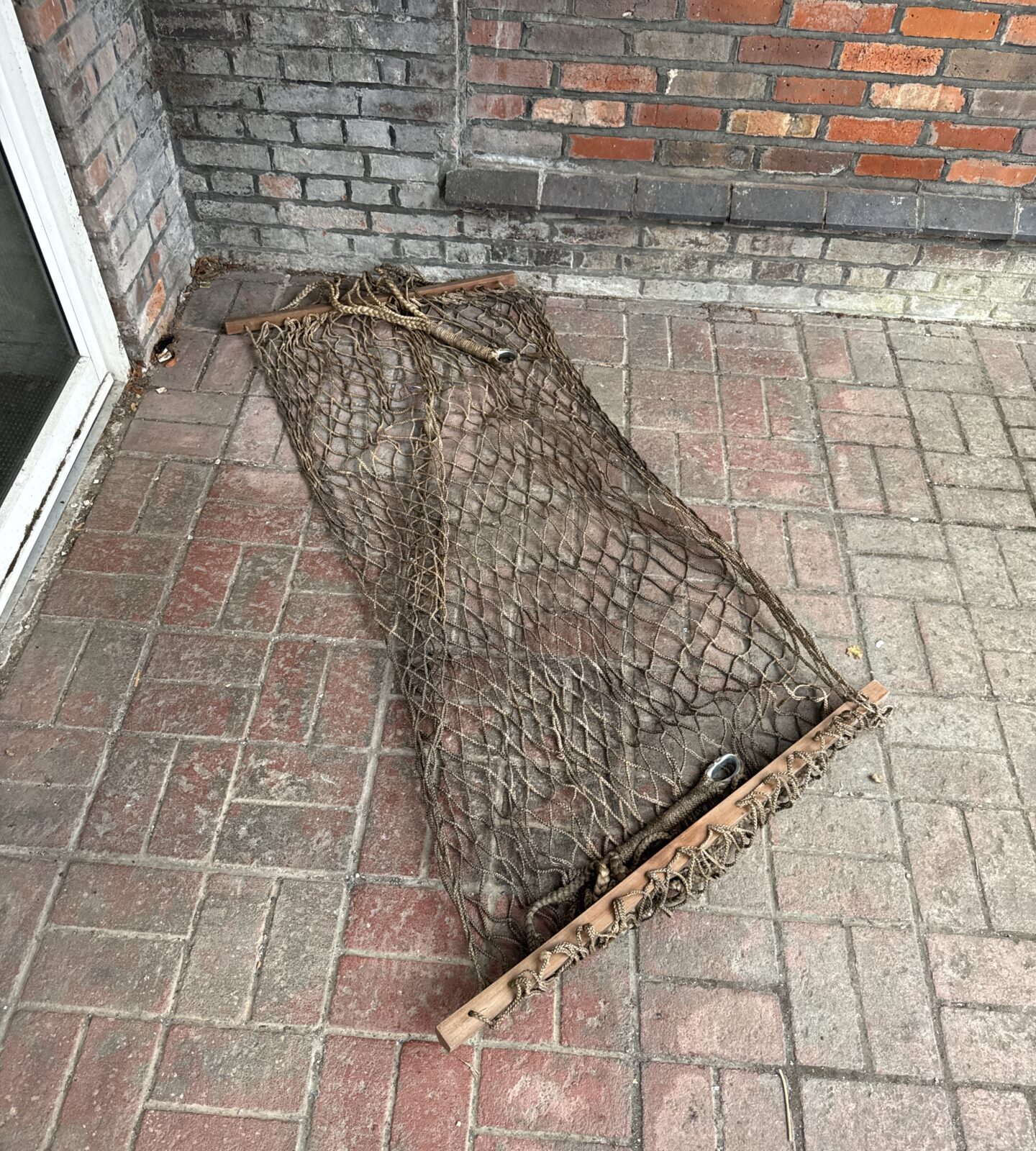 Vintage rope hammock with wooden spreader bars, ideal for outdoor relaxation.