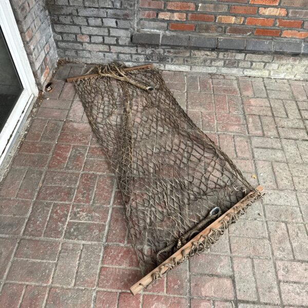 Vintage rope hammock with wooden spreader bars, ideal for outdoor relaxation.