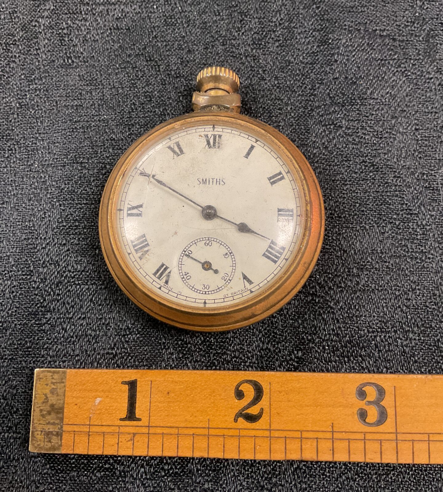 Vintage Smiths pocket watch with white enamel dial and Roman numerals.