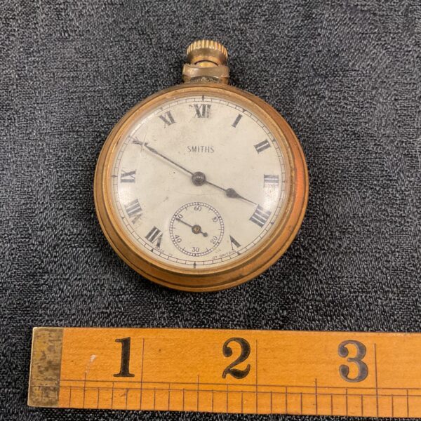Vintage Smiths pocket watch with white enamel dial and Roman numerals.