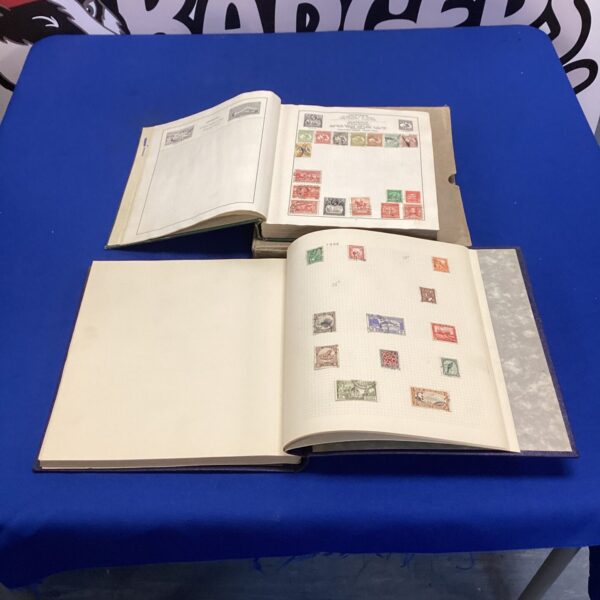 Two vintage stamp albums open, displaying a collection of stamps.