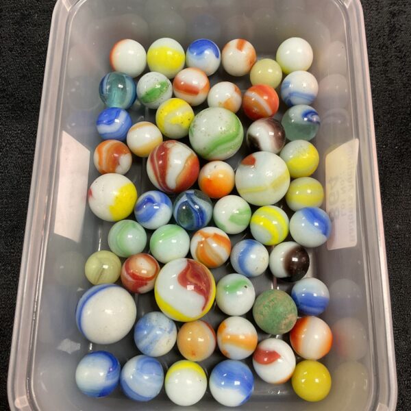 Lot of vintage uranium glass marbles glowing in a plastic tub.