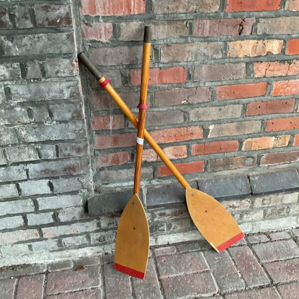 Pair of vintage wooden boat oars with red accents.