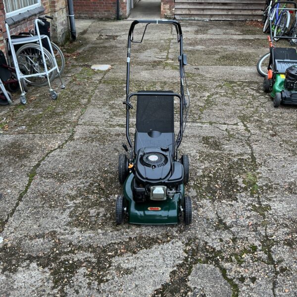 Vintage Webb 350 petrol lawnmower in a garden setting.