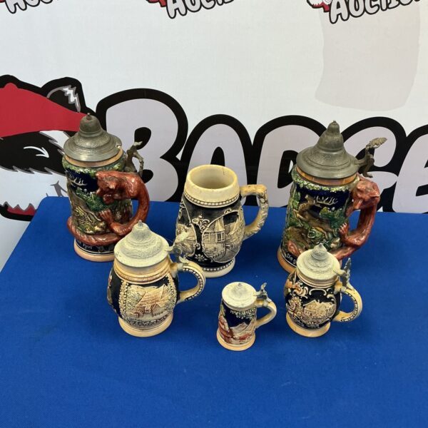Lot of vintage West German beer steins with detailed ceramic designs.