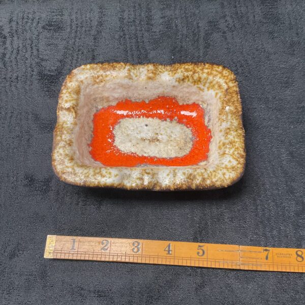 Vintage West German pottery ashtray with orange interior.