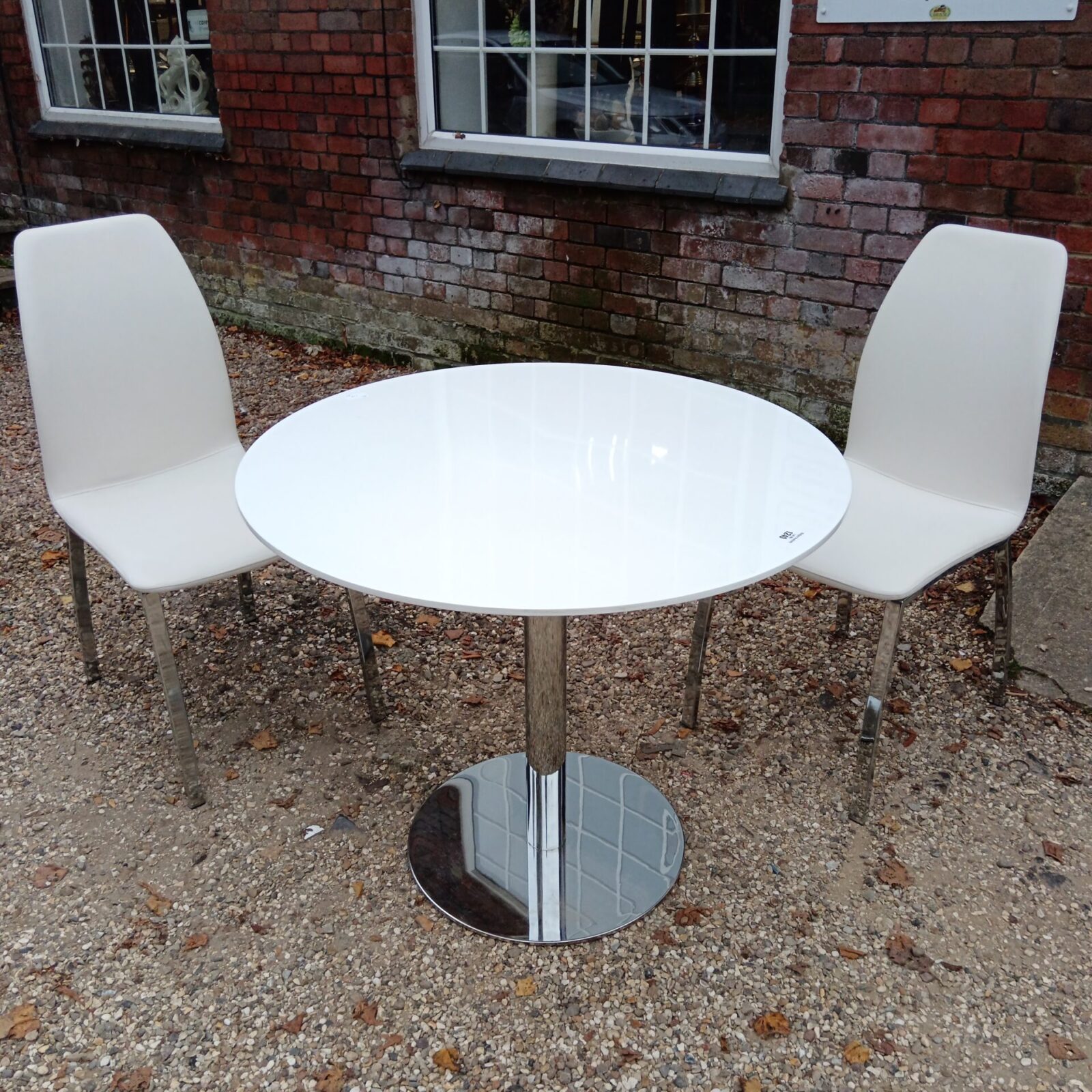 Modern white dining table and two chairs set in a home setting.