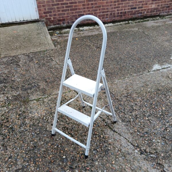 White folding step ladder for household use, showing signs of wear.