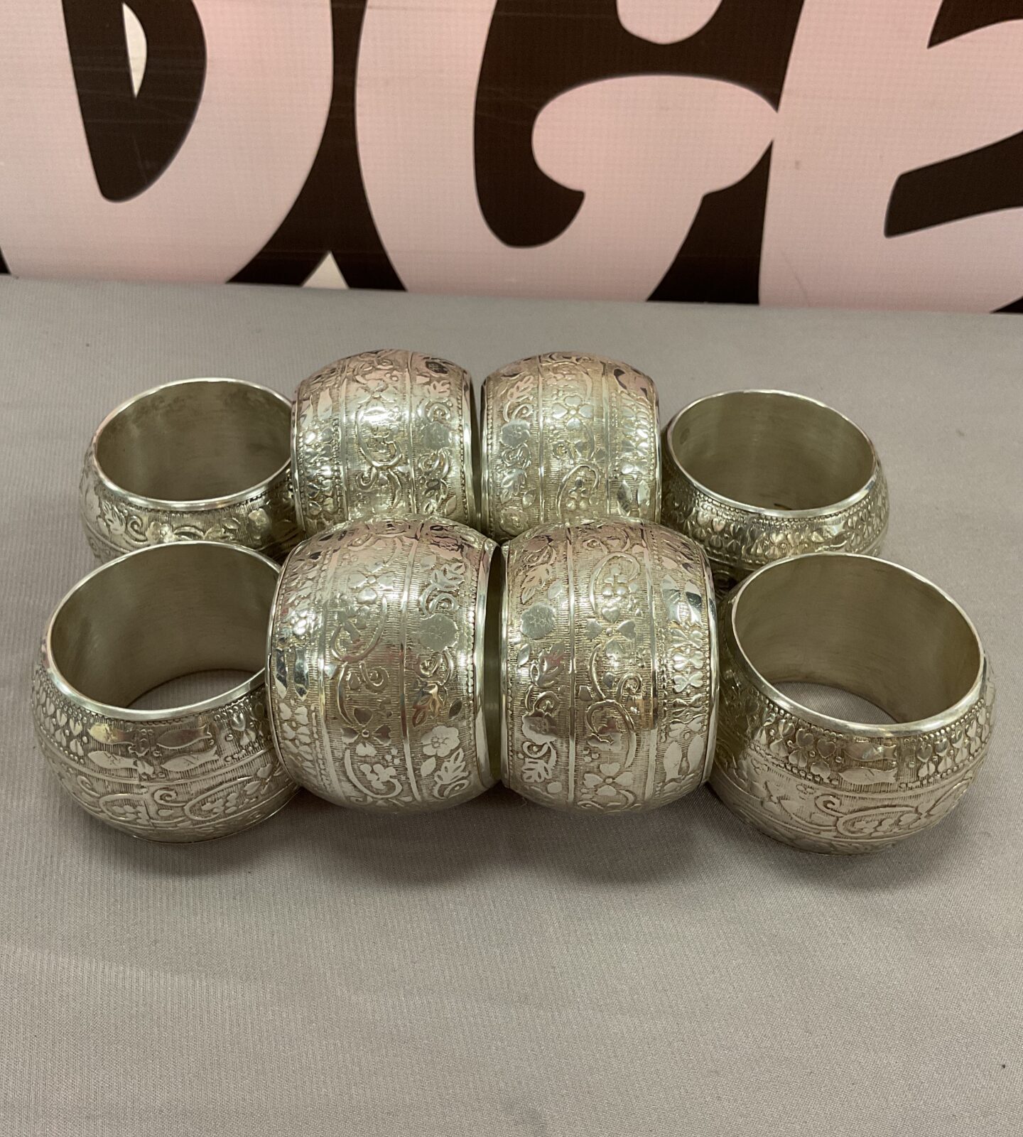 Set of eight vintage white metal serviette rings with floral designs.