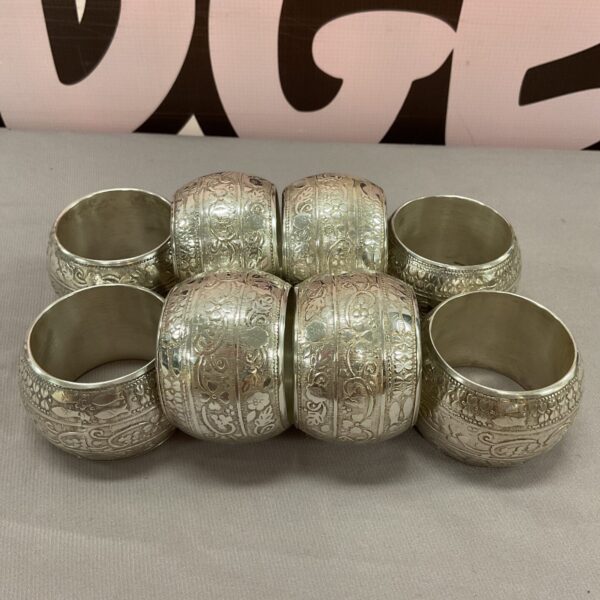Set of eight vintage white metal serviette rings with floral designs.