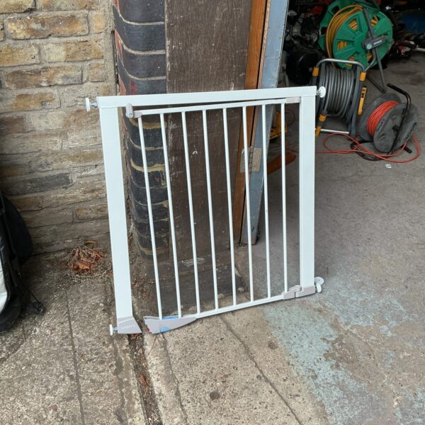 White stair safety gate for child security and hallway access.