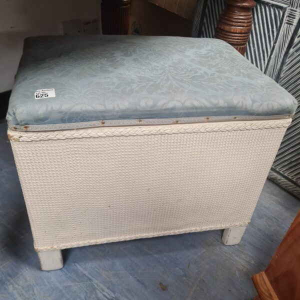 Vintage wicker footstool with blue patterned cushion, side view.