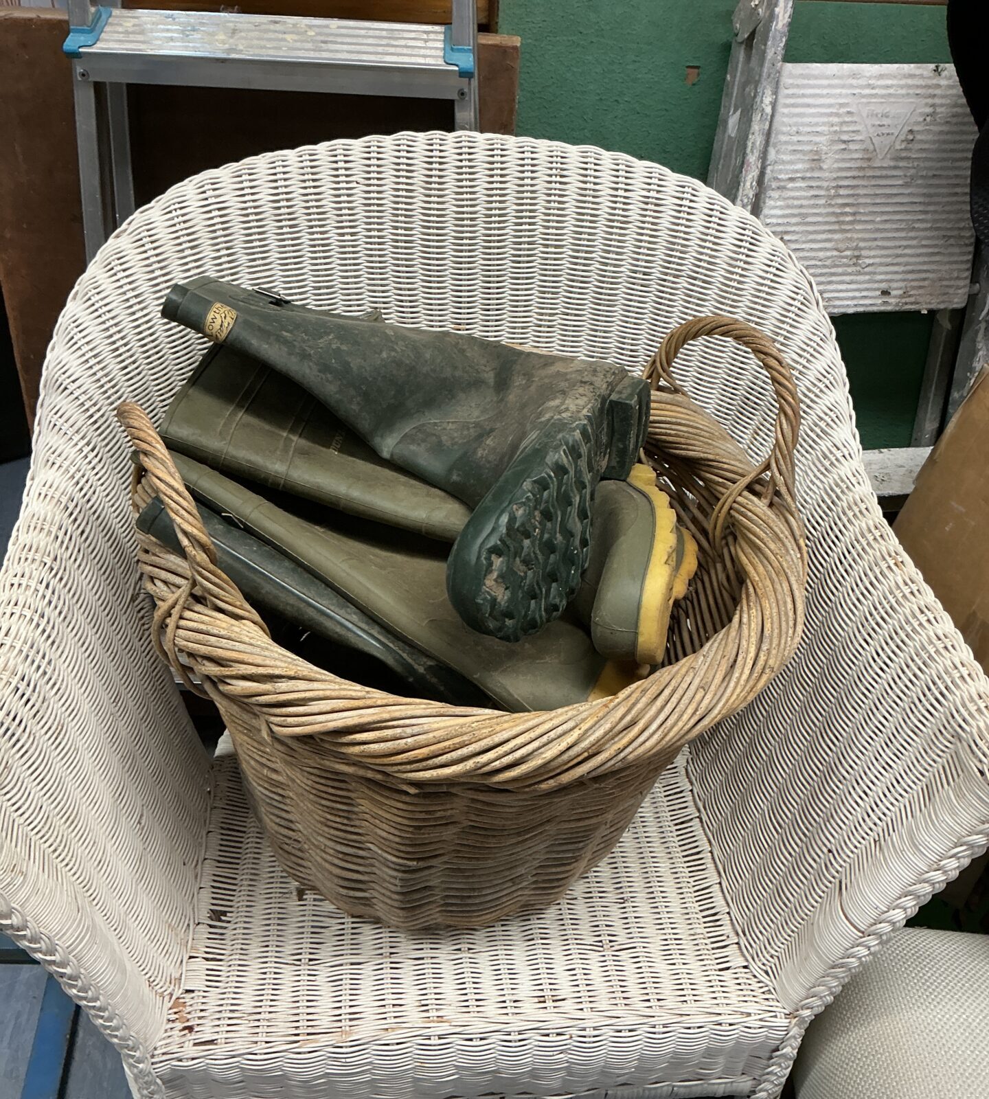 Vintage wicker log basket with wellington boots for country home.