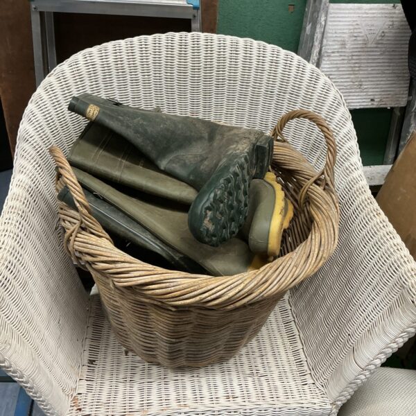 Vintage wicker log basket with wellington boots for country home.