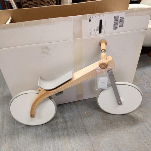 Side view of a wooden balance bike for toddlers.