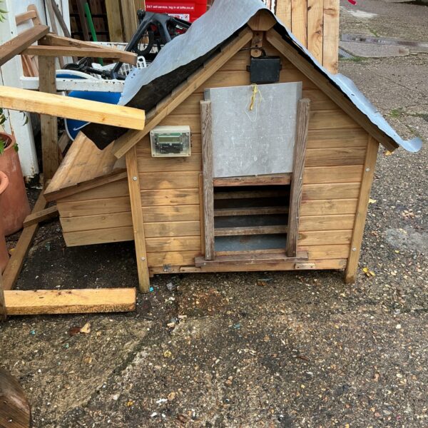 Front view of a rustic wooden chicken house in a garden.