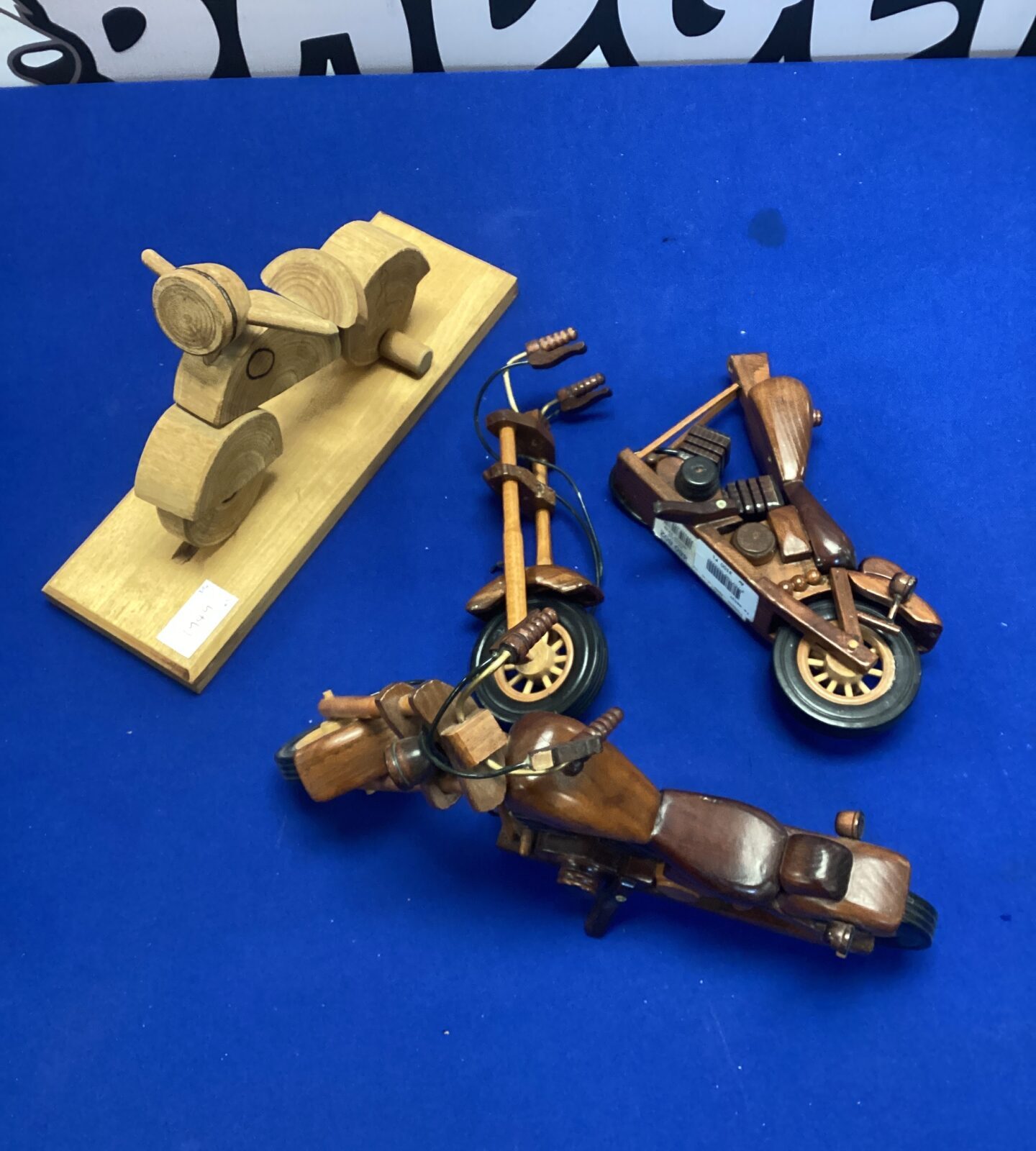 Set of three vintage wooden motorcycle ornaments on blue background.