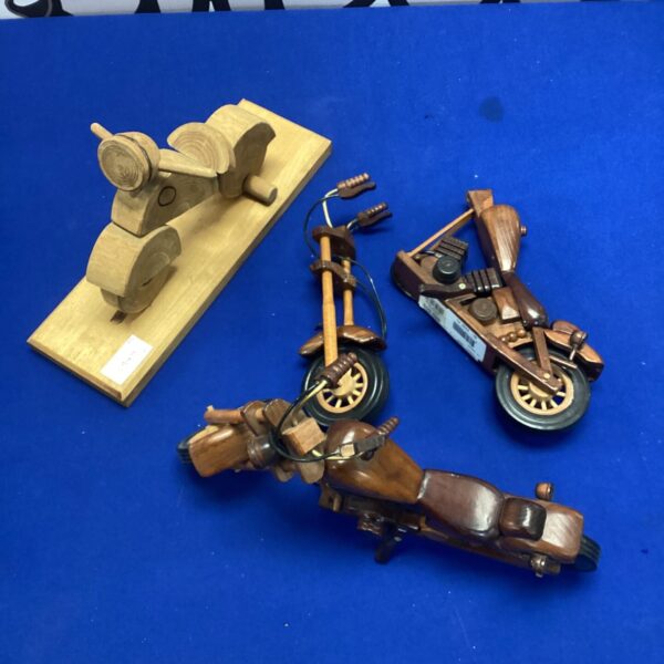 Set of three vintage wooden motorcycle ornaments on blue background.