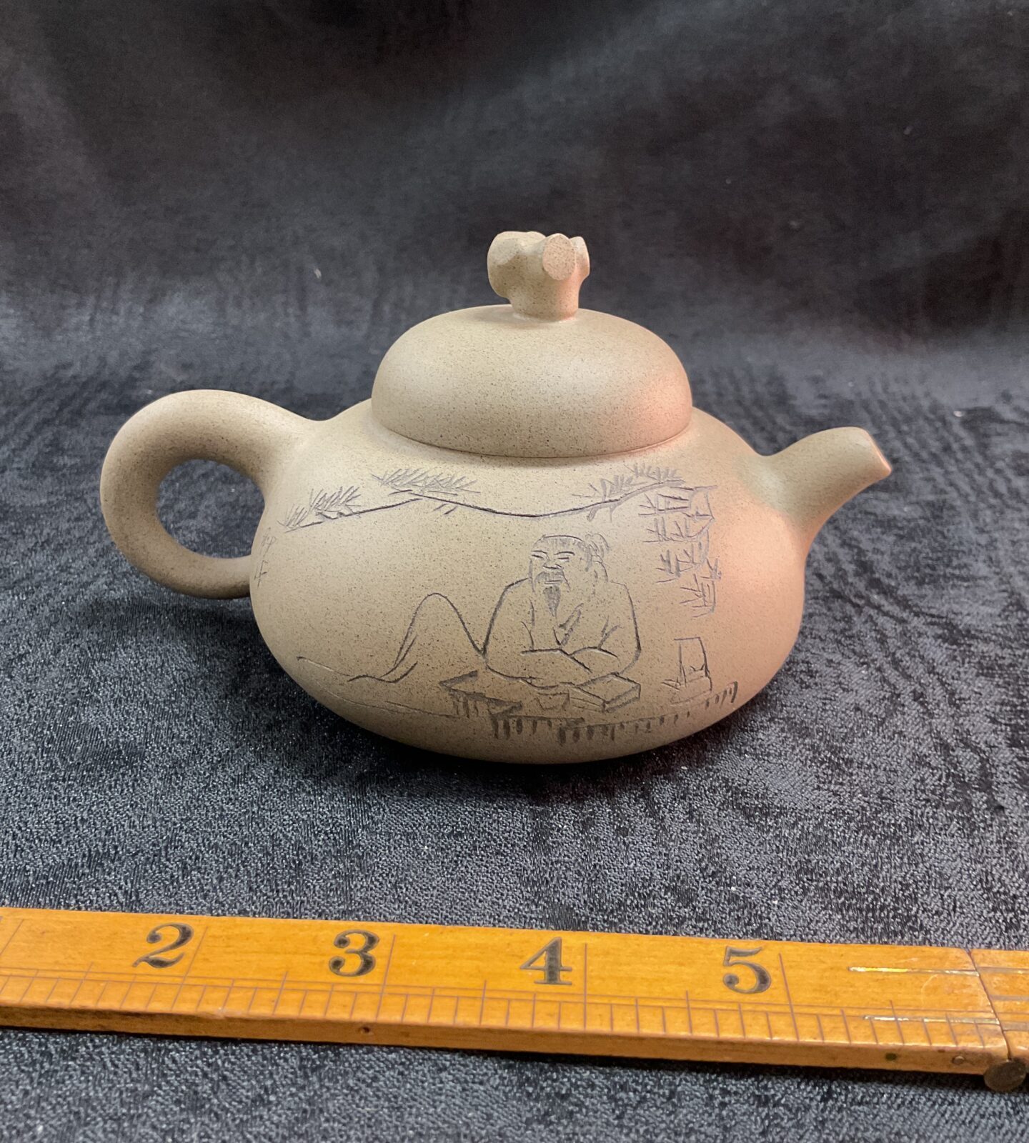 Intricate handmade Yixing teapot with carved landscape scene.