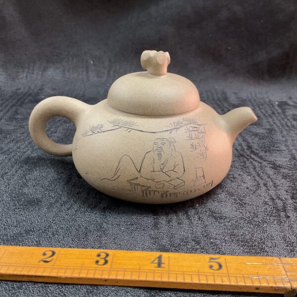 Intricate handmade Yixing teapot with carved landscape scene.