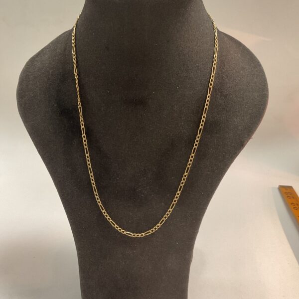 Close-up of a delicate 9ct gold figaro chain necklace.
