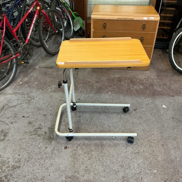 Adjustable bedside table with rolling casters and laminate top.