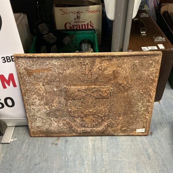 Antique cast iron fireplace back with a shield crest design.